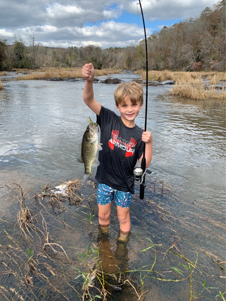 young boy smiling with fish and fishing pole in Flint River Upson County, GA